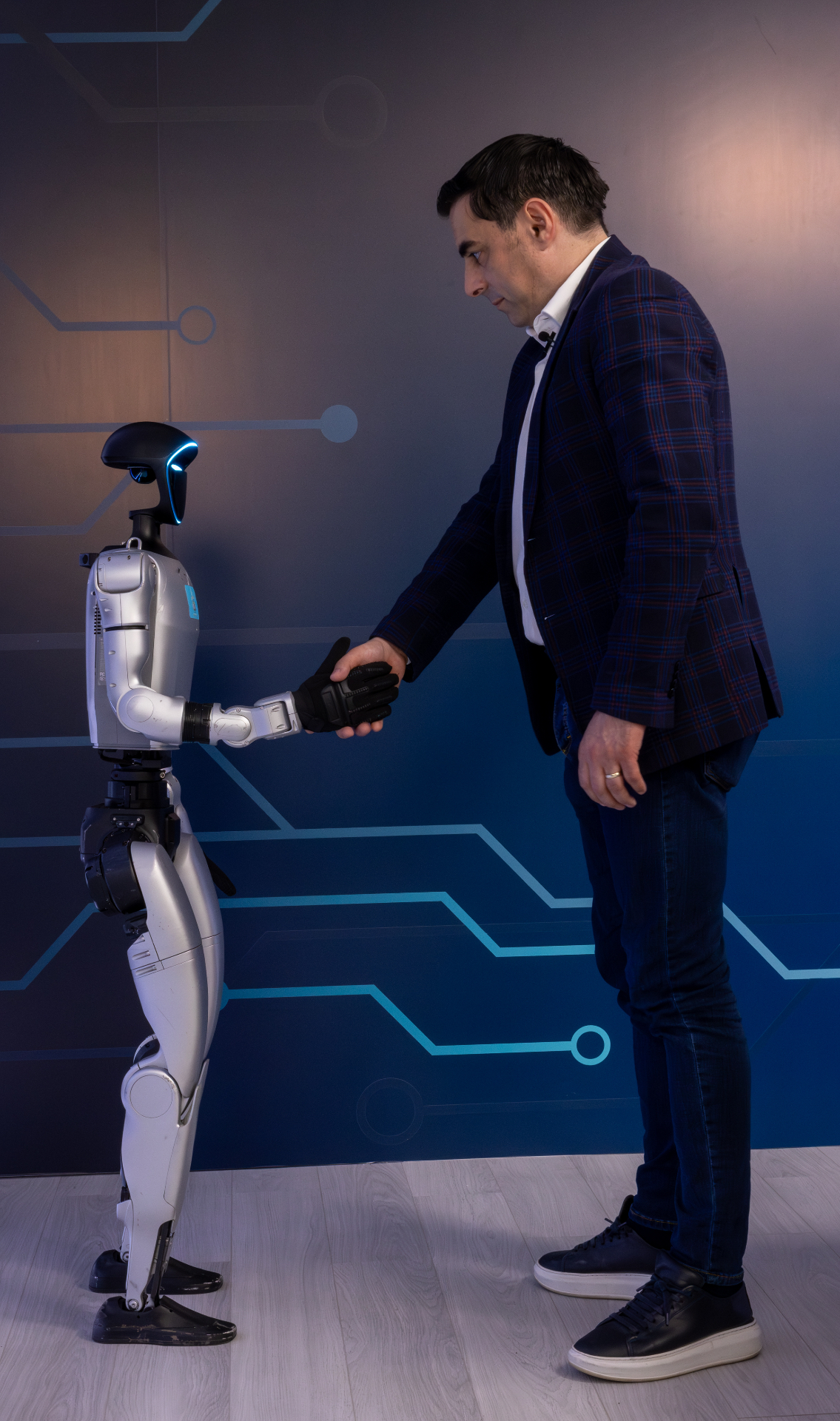 Cristian Lăcraru shaking hands with a humanoid educational robot